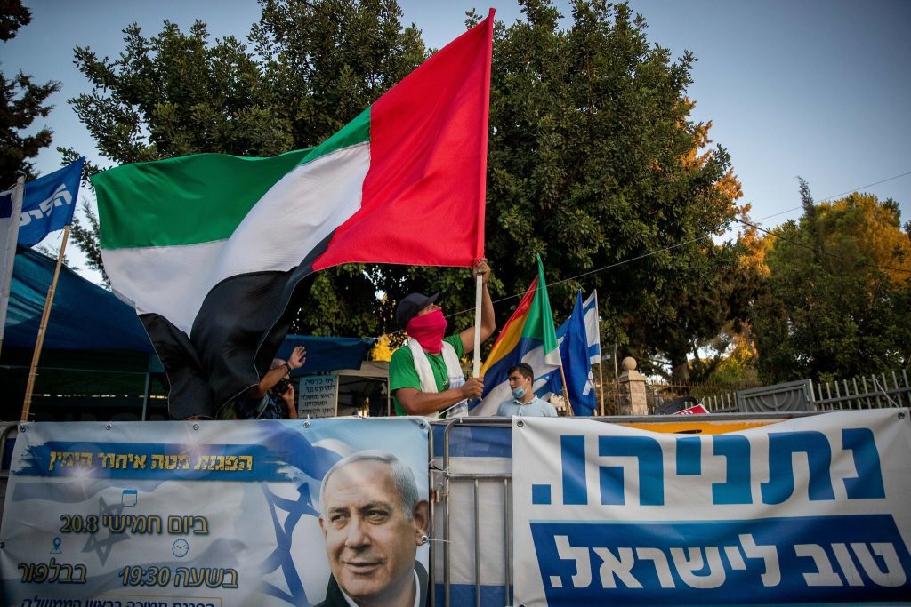 Un homme brandit un drapeau émirati géant devant la résidence officielle du Premier ministre à Jérusalem, le 19 août 2020. (Crédit : Yonatan Sindel/Flash90)