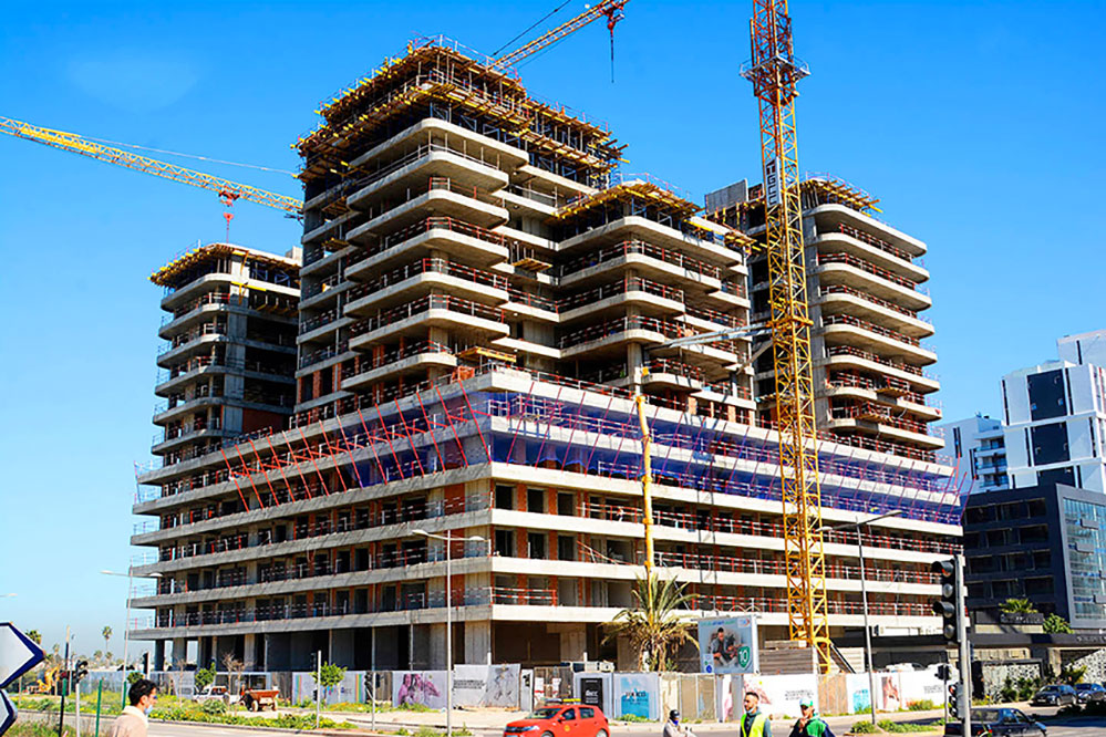 Chantier de construction d’un immeuble moderne avec plusieurs étages en cours de réalisation, entouré de grues, illustrant le dynamisme du secteur du BTP au Maroc.
