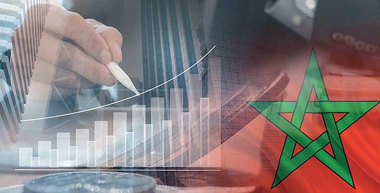 Graphique de croissance économique superposé à la main d’un analyste et au drapeau du Maroc, symbolisant le développement financier et l’évolution des marchés marocains