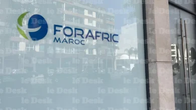 Logo de Forafric Maroc affiché sur une façade vitrée d’un bâtiment moderne, avec une porte d’entrée à droite et des reflets urbains en arrière-plan.