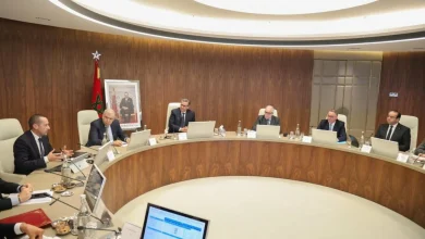 Réunion présidée par Aziz Akhannouch à Rabat sur la réforme du système de santé, avec des responsables autour d’une table de pilotage et le drapeau marocain en arrière-plan