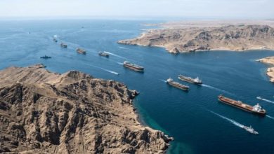 Vue aérienne du détroit d’Ormuz avec plusieurs pétroliers en circulation entre les côtes arides, illustrant un axe stratégique du transport mondial de pétrole au cœur des tensions entre l’Iran et les États-Unis.