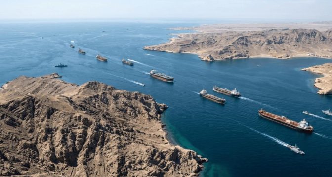 Vue aérienne du détroit d’Ormuz avec plusieurs pétroliers en circulation entre les côtes arides, illustrant un axe stratégique du transport mondial de pétrole au cœur des tensions entre l’Iran et les États-Unis.