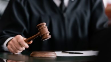 Un juge en robe noire frappe un marteau de justice sur son socle, posé sur un bureau, symbolisant une décision judiciaire ou le rendu d’un verdict.