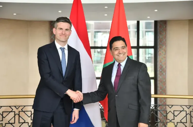 Nasser Bourita et le ministre des Affaires étrangères des Pays-Bas se serrant la main à Rabat devant les drapeaux marocain et néerlandais lors d’une rencontre diplomatique