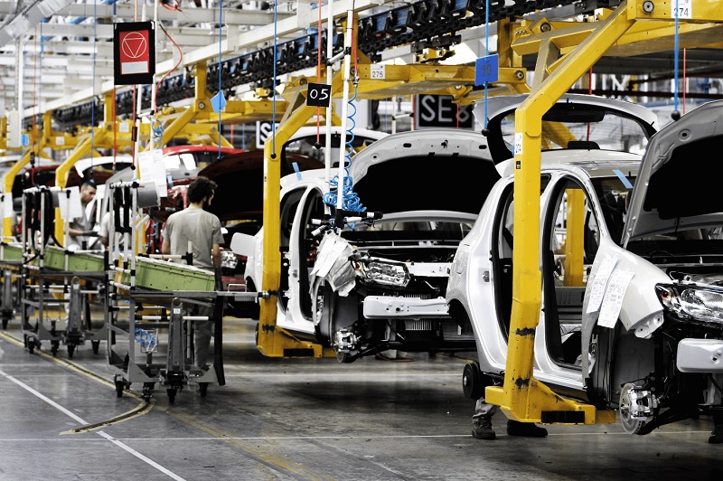Usine automobile au Maroc avec une chaîne de montage industrielle où plusieurs véhicules en cours d’assemblage sont alignés dans une unité de production moderne, illustrant le développement du secteur automobile marocain et sa montée en puissance industrielle.